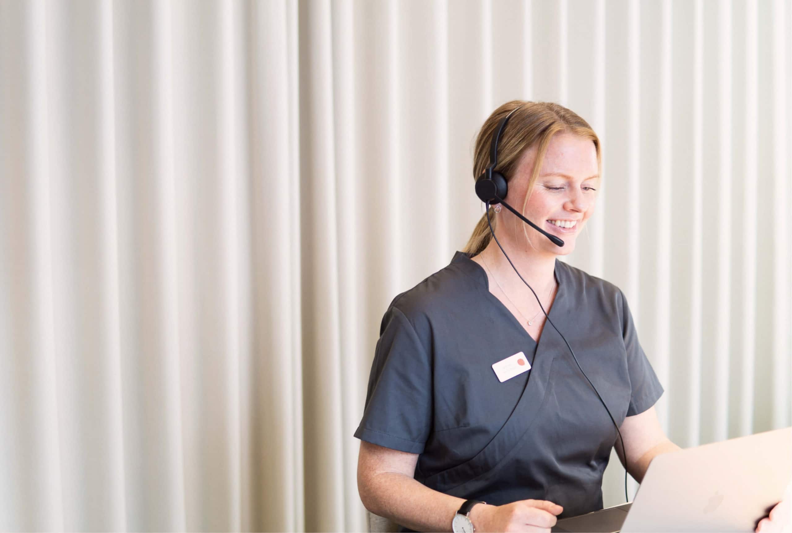 Sjuksköterska med headset ger sjukvårdsrådgivning och stöd vid sjukfrånvaro för snabbare återgång i arbete